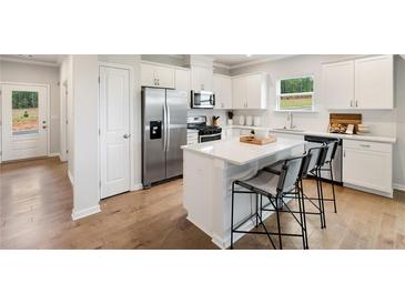 Bright kitchen features a center island, stainless steel appliances, and white cabinetry at 443 Village Ln, Fairburn, GA 30213