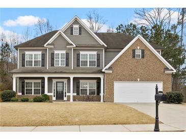 Charming two-story home featuring a mix of siding and brick, complemented by a well-manicured front yard and covered front porch at 6120 Sparrow Ln, Cumming, GA 30028
