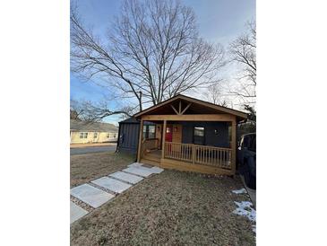 Charming home with a covered porch and inviting red door nestled under a bare tree against a clear blue sky at 205 Scott Nw St, Atlanta, GA 30314