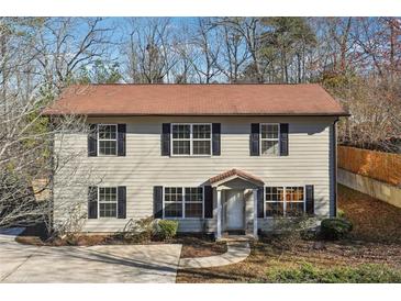 Two-story home featuring neutral siding, black shutters, a brown roof, and mature trees and landscaping at 3683 Rolling Pl, Conley, GA 30288