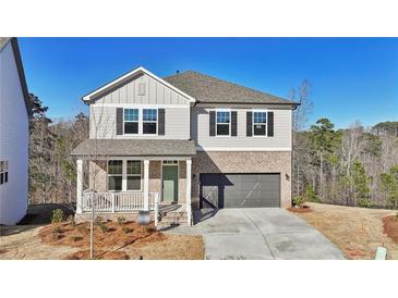 Charming two-story home with brick accents, a covered porch, and a two-car garage, set against a backdrop of trees at 688 Calvet Way, Cumming, GA 30041