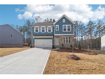 Two-story home featuring a stone facade, attached two-car garage, and a long concrete driveway at 7260 Eton Ln, Locust Grove, GA 30248
