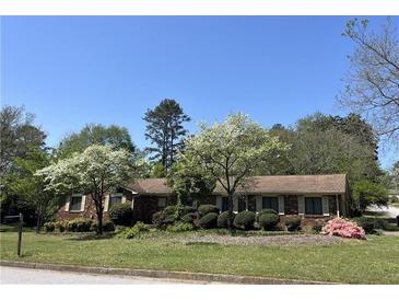 Charming brick home with lush landscaping and flowering trees in the front yard at 3557 Clubhouse Ln, Conyers, GA 30094