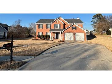 Two-story brick home featuring an attached two-car garage and well-manicured landscaping at 575 Dunagan Dr, Lawrenceville, GA 30045