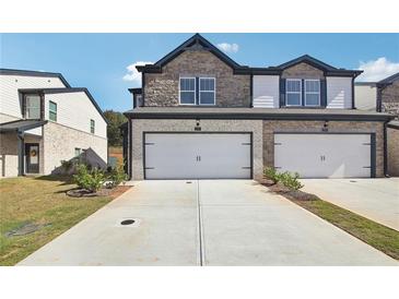 Two-story townhome with attached two-car garage, and landscaped front yard at 301 White Tail Rd, Stockbridge, GA 30253