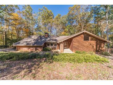 Brick and wood house with large windows, nestled in a wooded setting at 2612 Country Club Se Dr, Conyers, GA 30013