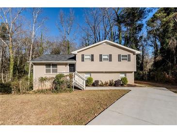 Two-story house with a beige exterior, landscaping, and driveway at 4412 Rustic Wood Dr, Stone Mountain, GA 30083