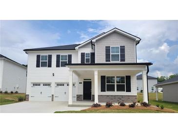 Charming two-story home with a two-car garage, covered porch, and landscaped front yard offers an inviting curb appeal at 146 Oakchase Park Ln, Hampton, GA 30228