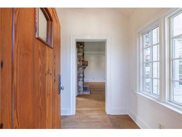 Bright entryway with hardwood floors, wood door, and view to living room with stone fireplace at 2853 N Hills Ne Dr, Atlanta, GA 30305