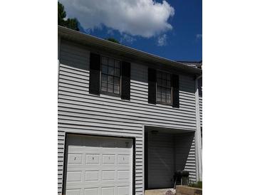 Two-story townhome with gray siding, black shutters, and a white garage door at 2511 Pine Tree Trl, Atlanta, GA 30349