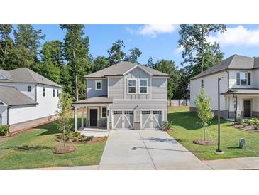 Two-story home with gray siding, two-car garage, and landscaped lawn at 1908 Holmsey Se Cir, Conyers, GA 30094