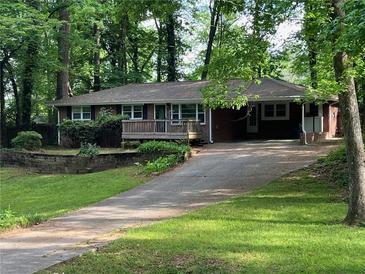 Charming one-story brick home with a front deck, mature trees, and a long driveway at 4876 Velva Nw Way, Lilburn, GA 30047