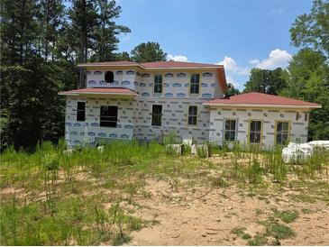 View of two-story home with red roof in construction phase and covered with protective wrap at 515 Penny Ln, Loganville, GA 30052