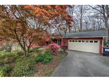 Charming red home featuring a two-car garage and well-manicured yard with vibrant flowering trees and bushes at 731 Willow Ridge Dr, Marietta, GA 30068