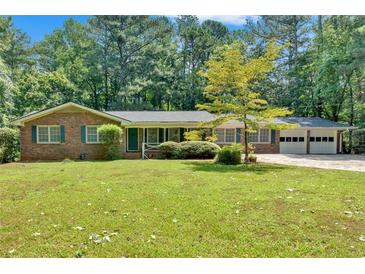 Charming single-story brick home with a well-manicured front lawn and attached two-car garage, surrounded by mature trees at 2144 Kennesaw Due West Nw Rd, Kennesaw, GA 30152