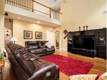 Spacious living room with high ceilings, hardwood floors, and a large entertainment center at 725 Martin Field Se Dr, Lawrenceville, GA 30045