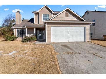 Tan two-story home with a two-car garage and a chimney, with a yard in need of maintenance at 5728 Rock Shoals Way, Atlanta, GA 30349