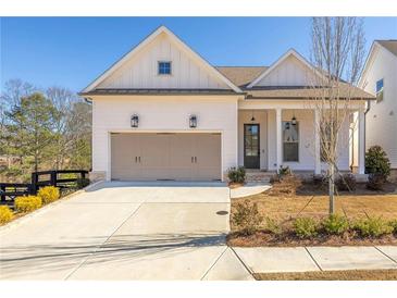 White farmhouse exterior with taupe garage doors and a covered porch at 210 Idylwilde Way, Canton, GA 30115