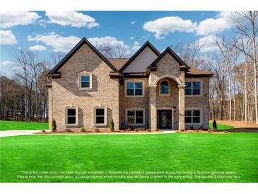 Stunning two-story brick home featuring a manicured lawn, stately architecture, and inviting curb appeal on a sunny day at 2571 Se Ebenezer Rd, Conyers, GA 30094