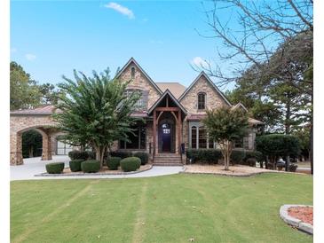 Charming stone home featuring manicured landscaping, a portico, gabled roof and a lush, green lawn at 1255 Mcminn Way, Snellville, GA 30078
