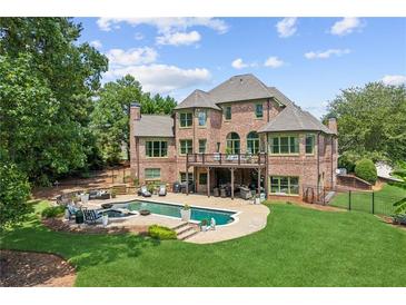 Luxury home backyard featuring a beautiful in-ground pool, spa, lounge area and lush landscaping at 3215 Kylee Dawn Cir, Lawrenceville, GA 30045