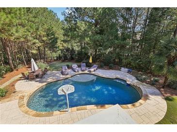 Aerial view of a beautiful backyard pool with lounge chairs and patio furniture surrounded by mature trees at 3950 Stanford Dr, Cumming, GA 30041