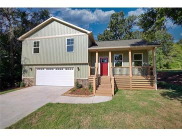 Newly constructed home featuring a light green exterior, a red front door, and a two-car garage at 520 Mountainview Dr, Covington, GA 30016