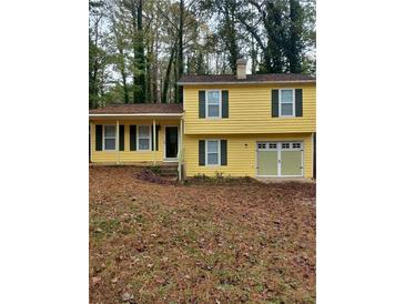 Cute yellow house with green shutters, a two-car garage, and a yard at 701 Boone Ct, Stone Mountain, GA 30088