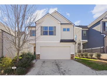 Two-story house with light beige siding, a white garage door, and a neatly landscaped lawn at 3948 Lake Manor Way, Atlanta, GA 30349