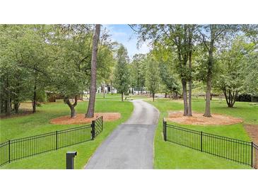 Long driveway leading to home, framed by lush landscaping and black iron fence at 9650 Coleman Rd, Roswell, GA 30075