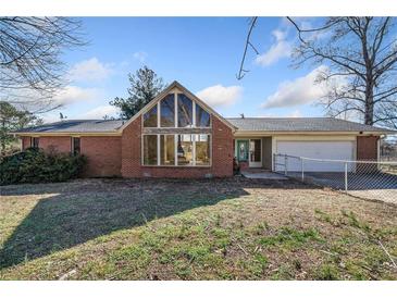 Brick ranch house with large window, attached garage, and fenced yard at 4386 Bluebird Ln, Lithia Springs, GA 30122