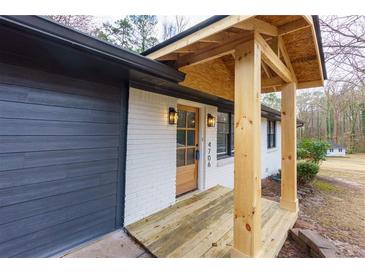 Inviting front porch with wood columns and modern light fixtures at 4706 Lincoln Sw Way, Lilburn, GA 30047