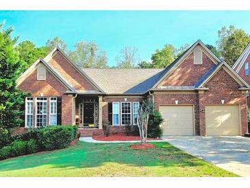 Brick home with 2-car garage, manicured lawn, and mature trees at 651 Hexham Ct, Suwanee, GA 30024