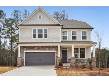 Charming two-story home with stone accents, gray siding, and a covered front porch at 7256 Eton Ln, Locust Grove, GA 30248