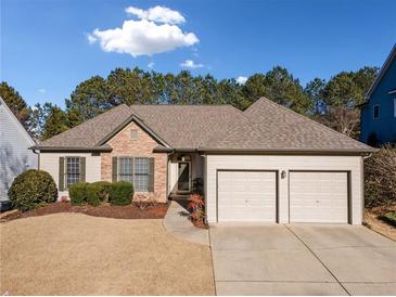 Brick and beige exterior boasts a two-car garage and manicured lawn at 3062 Woodbridge Ln, Canton, GA 30114