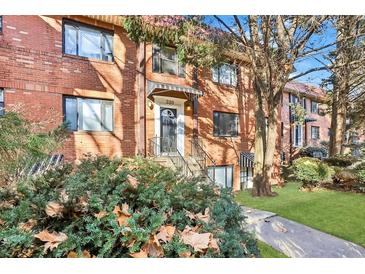 Charming brick townhouse featuring a black awning over the door, complemented by lush landscaping and a well-manicured lawn at 320 3Rd Ne St # 1, Atlanta, GA 30308