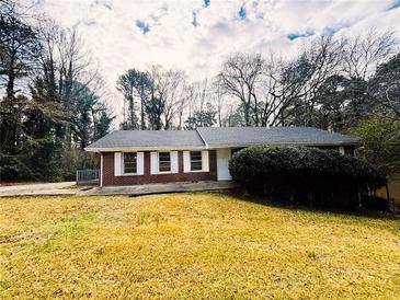 Charming brick ranch home with lush landscaping and a well-maintained yard on a sunny, partially cloudy day at 4515 Wonder Valley Trl, Decatur, GA 30034