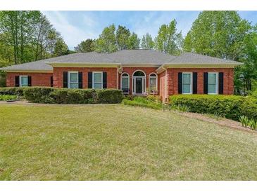 Brick ranch home with large windows, mature landscaping, and a spacious lawn at 1420 Arblay Pl, Loganville, GA 30052