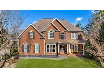 Brick two-story house with a landscaped lawn and a large driveway at 5507 Ashleigh Walk Nw Dr, Suwanee, GA 30024