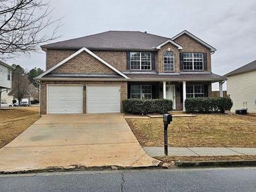 Brick two-story house with a two-car garage and landscaped front yard at 5852 Sunflower Ct, Ellenwood, GA 30294