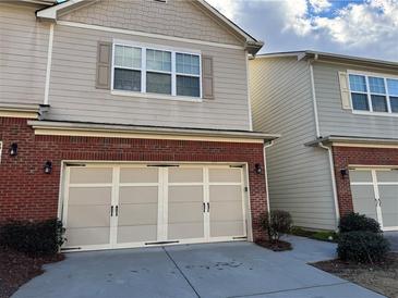 Tan brick front exterior of townhome with two-car garage at 981 Treymont Way, Lawrenceville, GA 30045