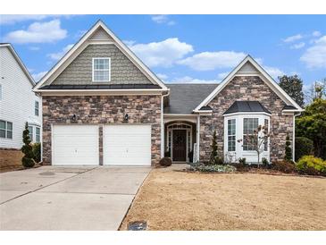 Charming stone-accented home featuring a two-car garage and inviting front porch, perfect for suburban living at 173 Mill Creek Dr, Canton, GA 30115
