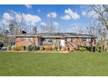 Charming brick home featuring a well-manicured lawn and inviting front porch at 7034 Capps Ferry Rd, Douglasville, GA 30135