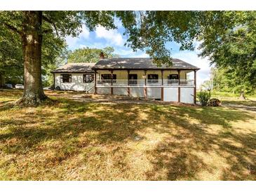 Ranch house with a large front porch, surrounded by lush landscaping at 3241 Briscoe Rd, Loganville, GA 30052