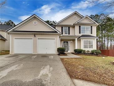 Two-story house with beige siding, two-car garage, and landscaped lawn at 129 Baywood Xing, Hiram, GA 30141