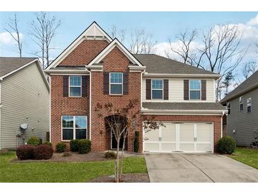 Two-story brick home with a three-car garage and landscaped lawn at 4705 Sanderling St, Cumming, GA 30041