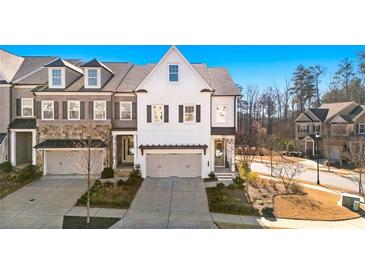 Three-story townhome with white exterior, two-car garage, and landscaping at 1 Ganel Ln, Alpharetta, GA 30009