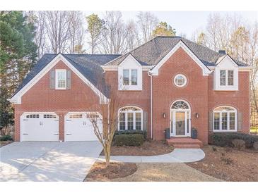 Brick two-story house with a three-car garage and landscaped yard at 9970 Groomsbridge Rd, Johns Creek, GA 30022