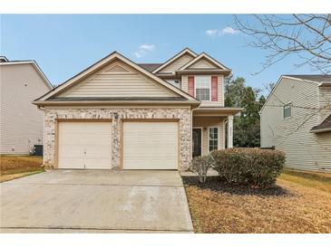 Two-story house with beige siding, brick accents, and a two-car garage at 6057 Hemperly Rd, Atlanta, GA 30349