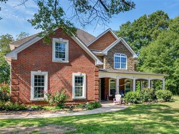 Brick house with stone accents, covered porch, and landscaped yard at 10 Toscanno Dr, Covington, GA 30014